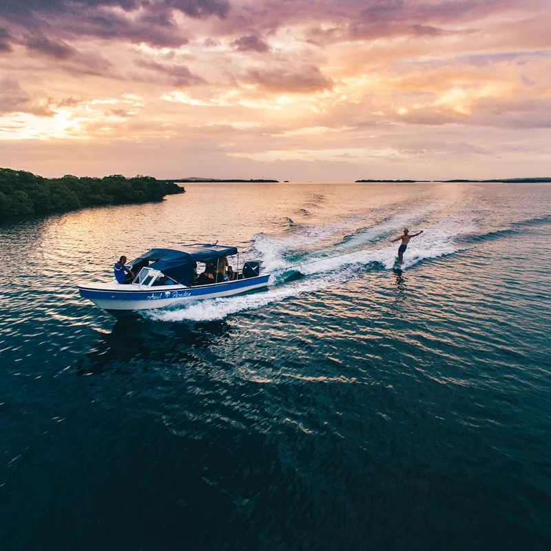 Riding the flat water behind a boat at sunset