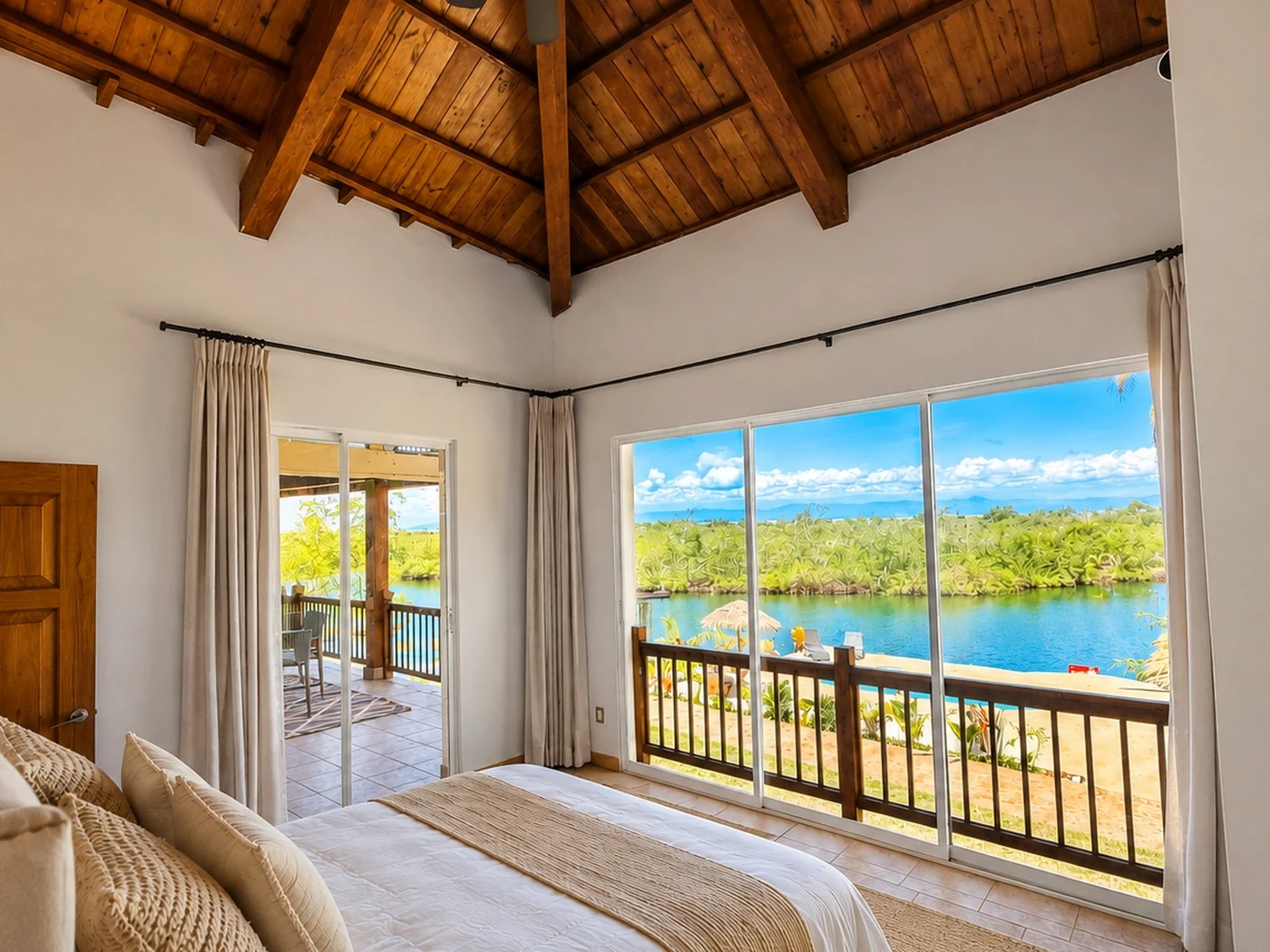 A bedroom under the vaulted hardwood ceiling, opening to the veranda and the canal